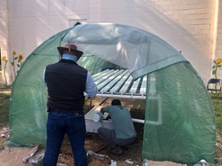 Two men assembling a high tunnel green house and hydroponics system